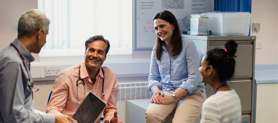 Group of clinicians sat in an office having a meeting and smiling