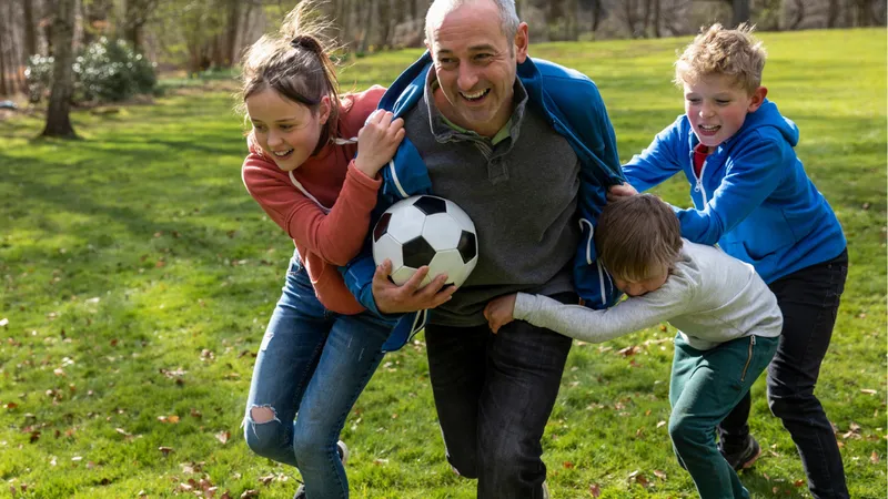 Image of a father playing football with three young children