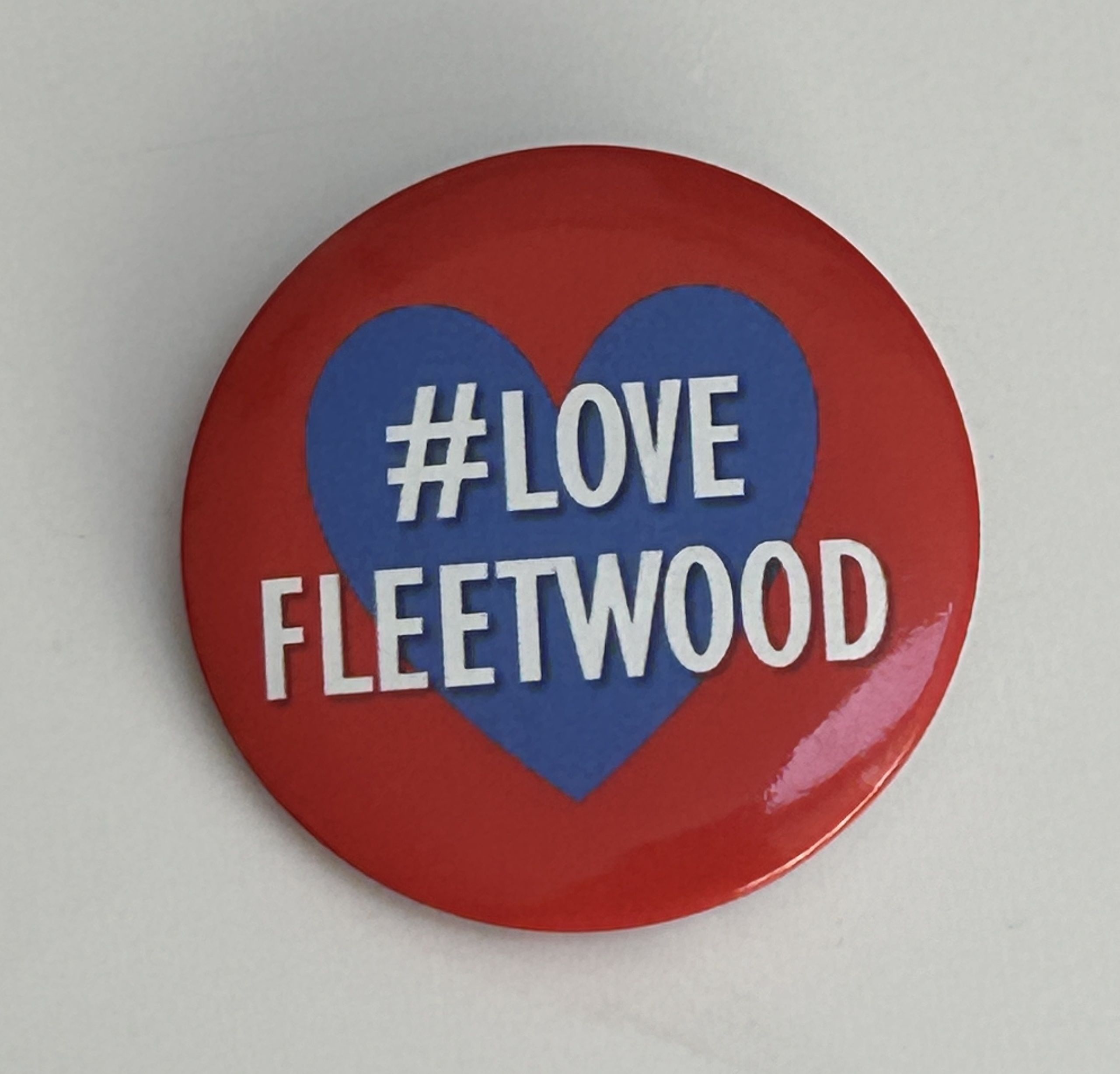 Red button with a blue heart, featuring the text 