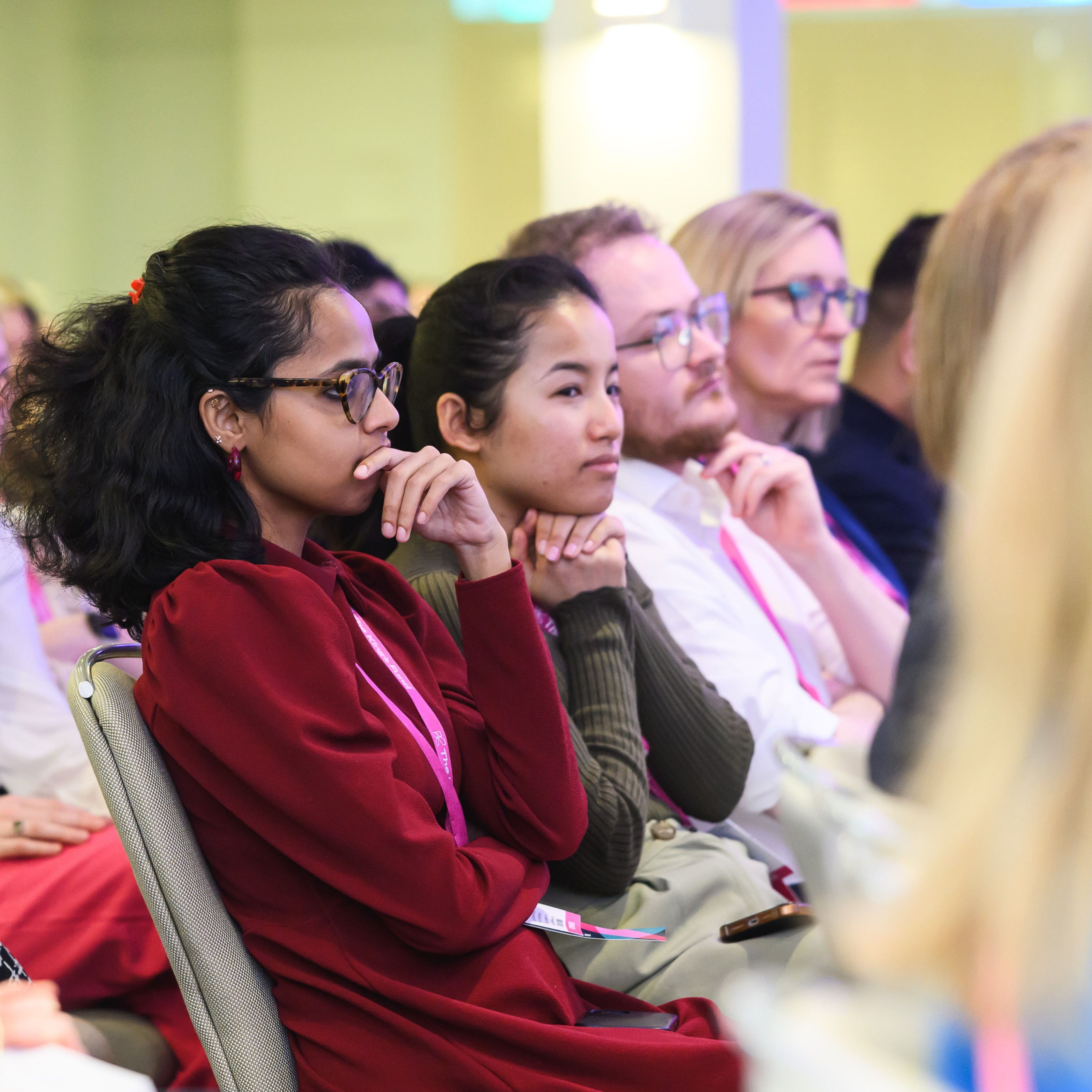 Four people sit in a row listening at an event.