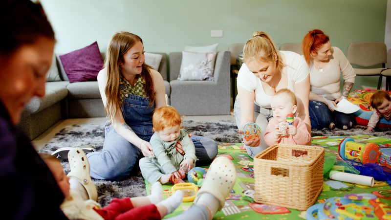 Image of two mothers playing with their babies.
